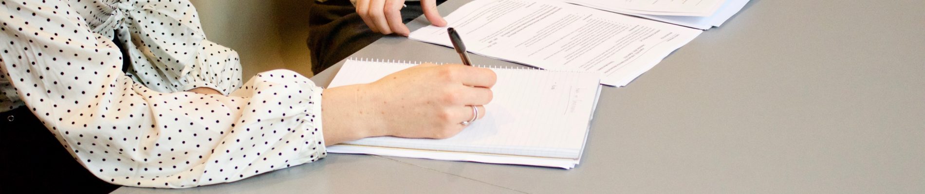 Deux femmes assises à une table signant des documents.