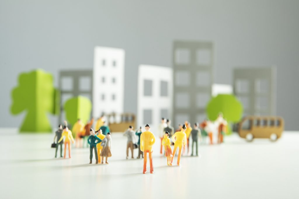 Des silhouettes de personnes en papier se tiennent devant une ville animée.